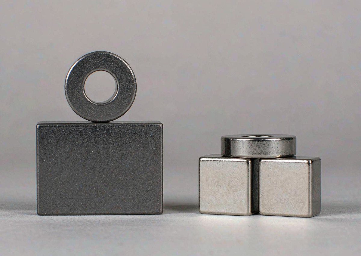Material comparison: matte samarium cobalt magnet beside nickel-plated neodymium magnets